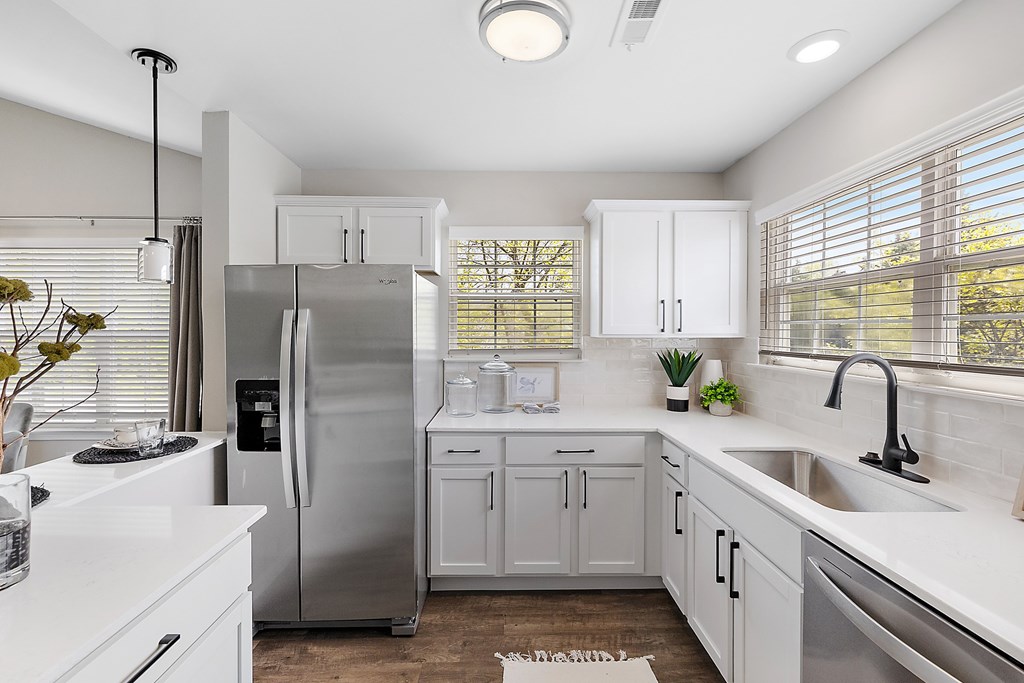 A modern kitchen with white cabinets and a stainless steel refrigerator.