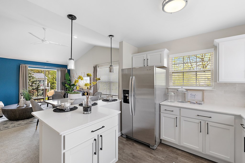 A modern kitchen with a stainless steel refrigerator and white cabinets.
