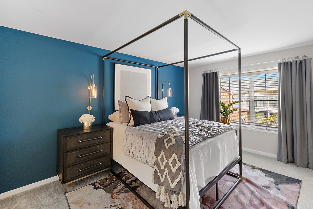 A bedroom with a four poster bed and a dresser.