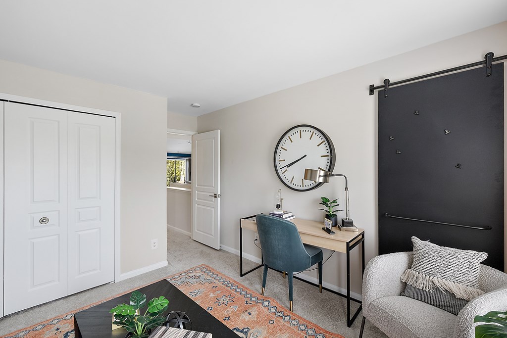 A room with a desk, chair, and clock on the wall.