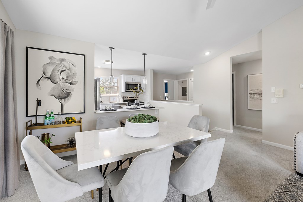 A dining room with a white table and chairs.