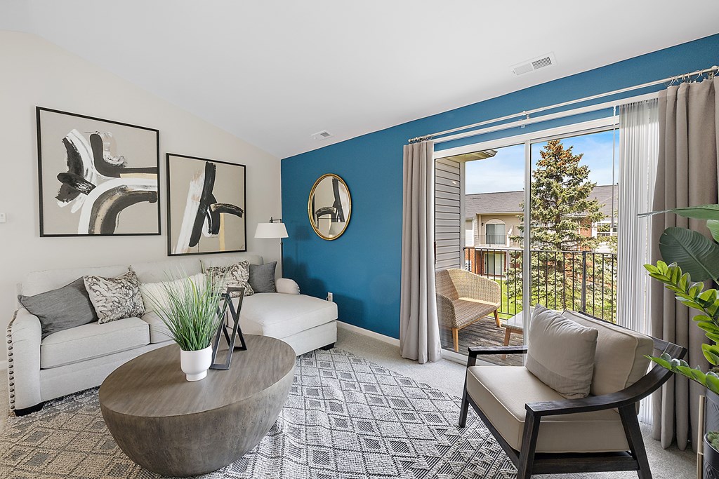 A living room with a white couch, a coffee table, and a large window with a view of a house and trees outside.