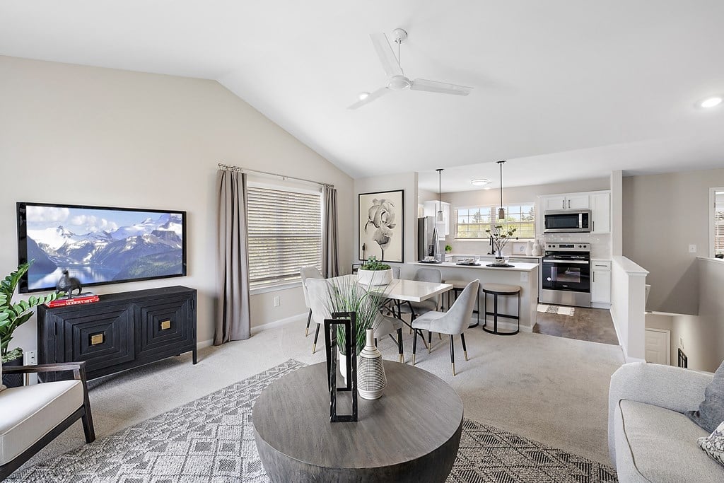 A living room with a television, a dining table, and chairs.