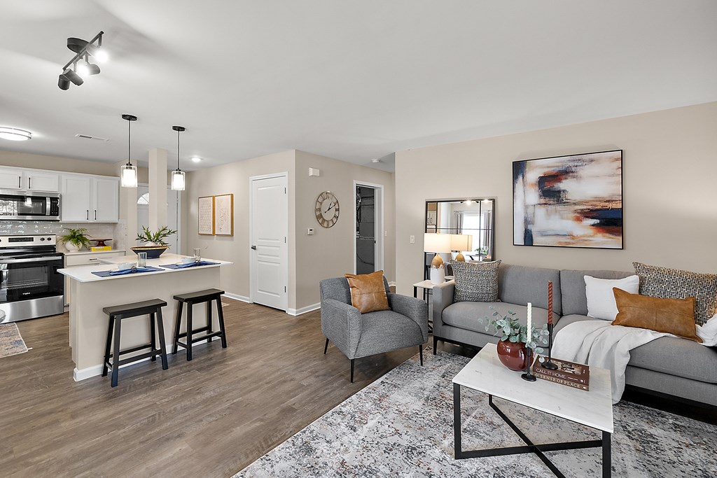 A modern living room with a kitchen area in the background.