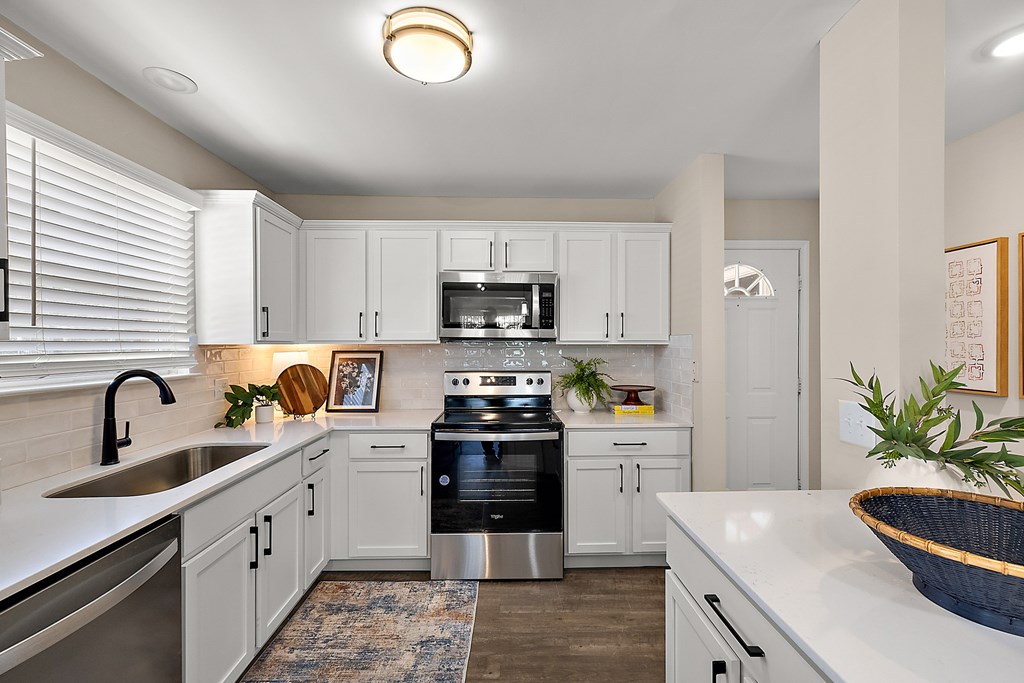 A modern kitchen with white cabinets and stainless steel appliances.