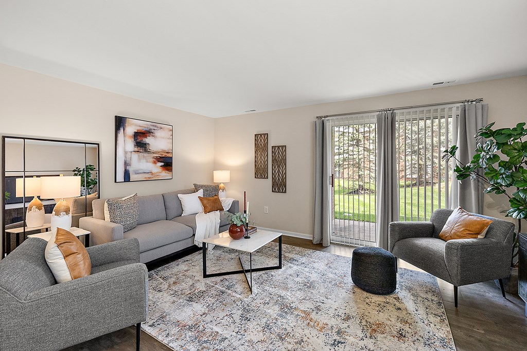 A living room with a grey couch, a grey armchair, a coffee table, and a rug.