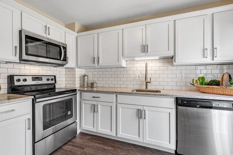 a white kitchen with stainless steel appliances and white cabinets
