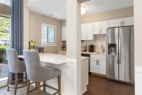 a kitchen with a bar and a stainless steel refrigerator