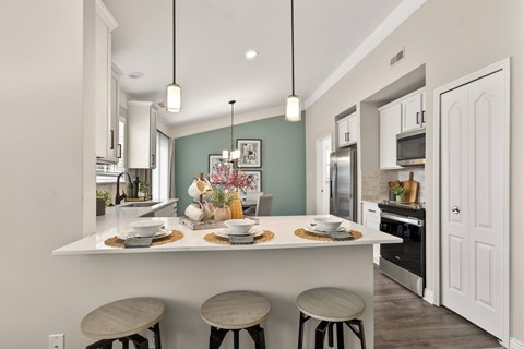 A kitchen with a white counter and three stools.