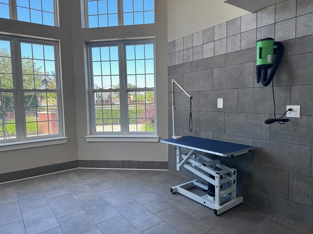 a treatment room with a table and a chair and three windows at Cidermill Village Apartments in Rochester Hills, MI 