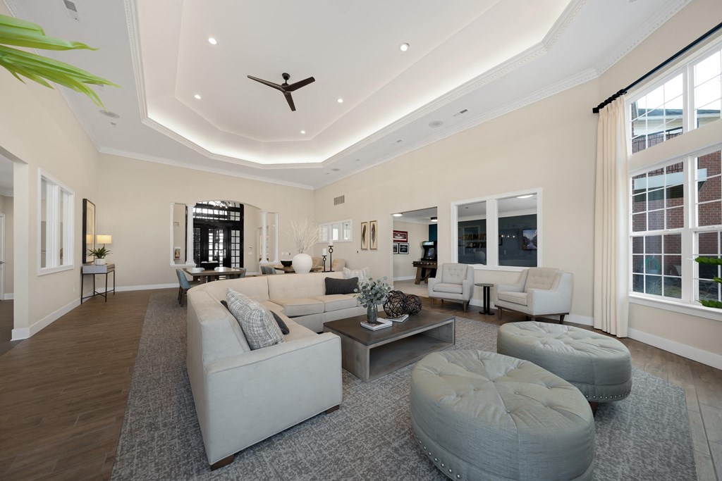 A spacious living room with a white sofa set and a grey ottoman at Cidermill Village Apartments in Rochester Hills, MI 