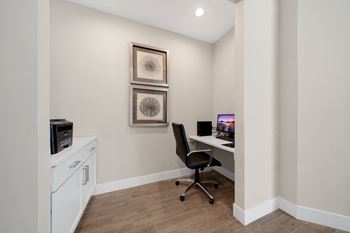 A room with a chair, a desk, and two pictures on the wall at Cidermill Village Apartments in Rochester Hills, MI 