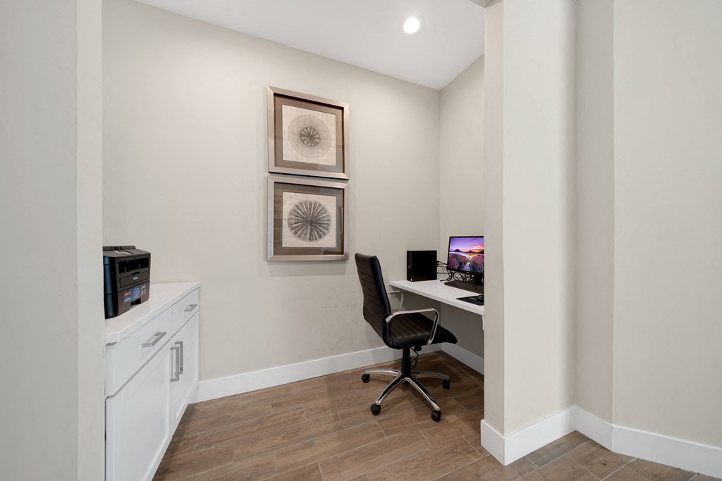 A room with a chair, a desk, and two pictures on the wall at Cidermill Village Apartments in Rochester Hills, MI 