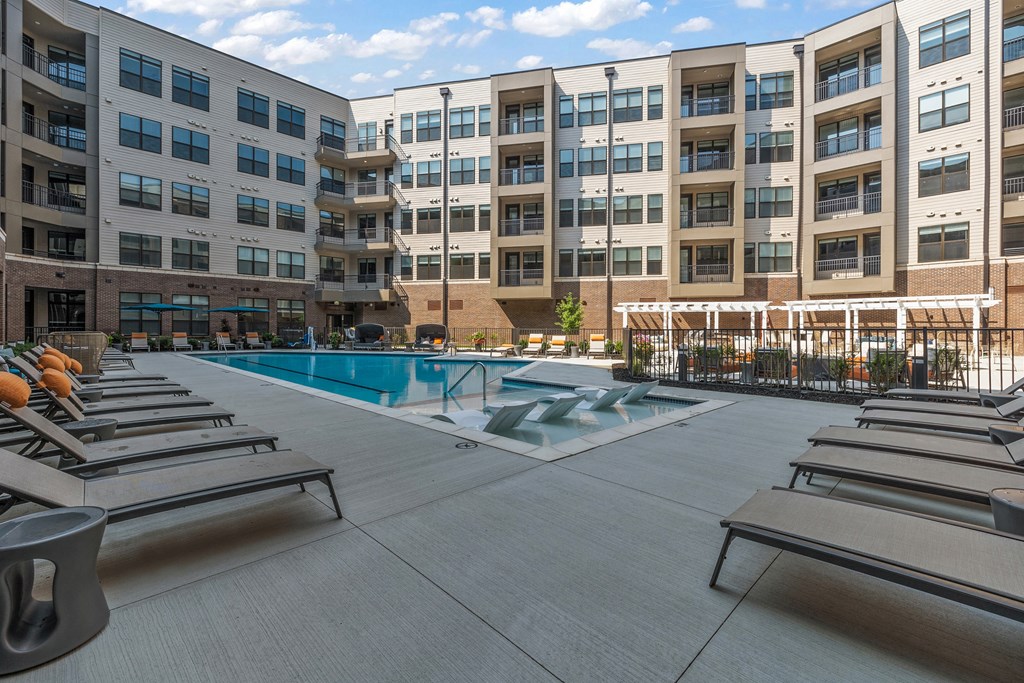 an outdoor pool with chaise lounge chairs and a building in the background  at The Griffin Royal Oak, Royal Oak, 48067
