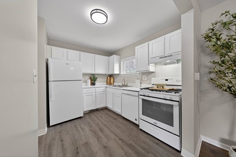 A kitchen with white appliances and wooden floors.