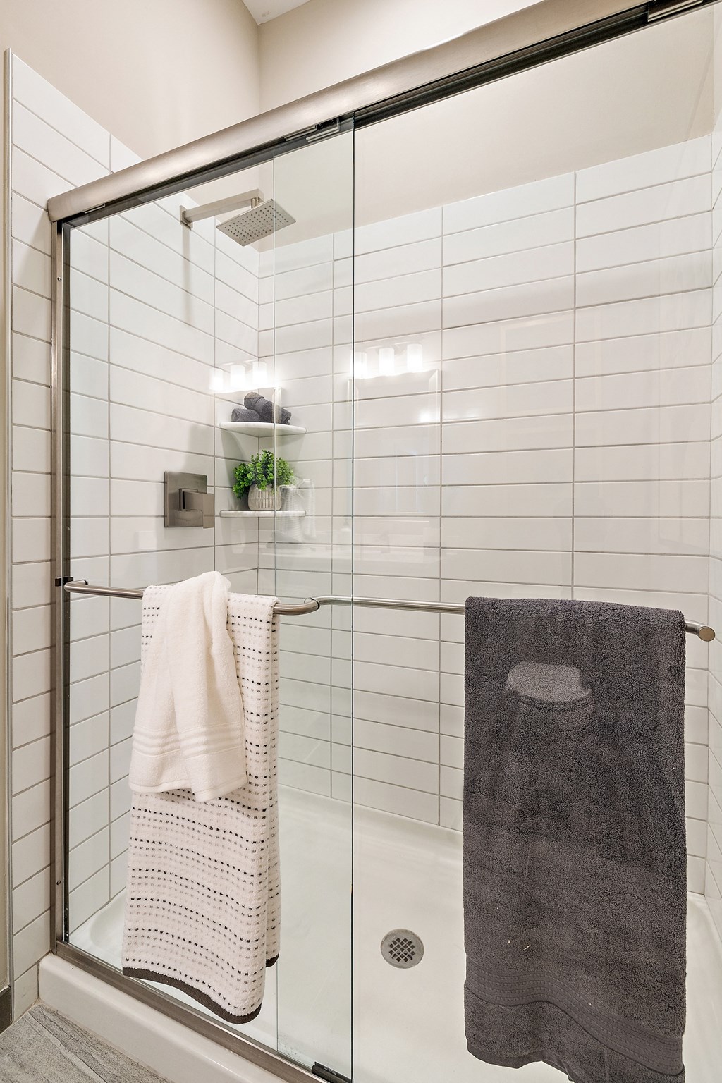 a small bathroom with white tiles and a glass shower door at The Griffin Royal Oak, Royal Oak, MI