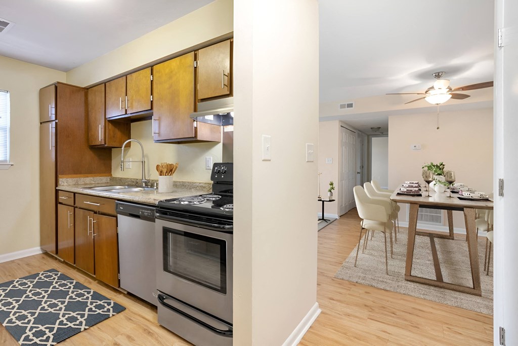 a kitchen with stainless steel appliances and a dining room table at West Pointe Apartments in Burlington, NC