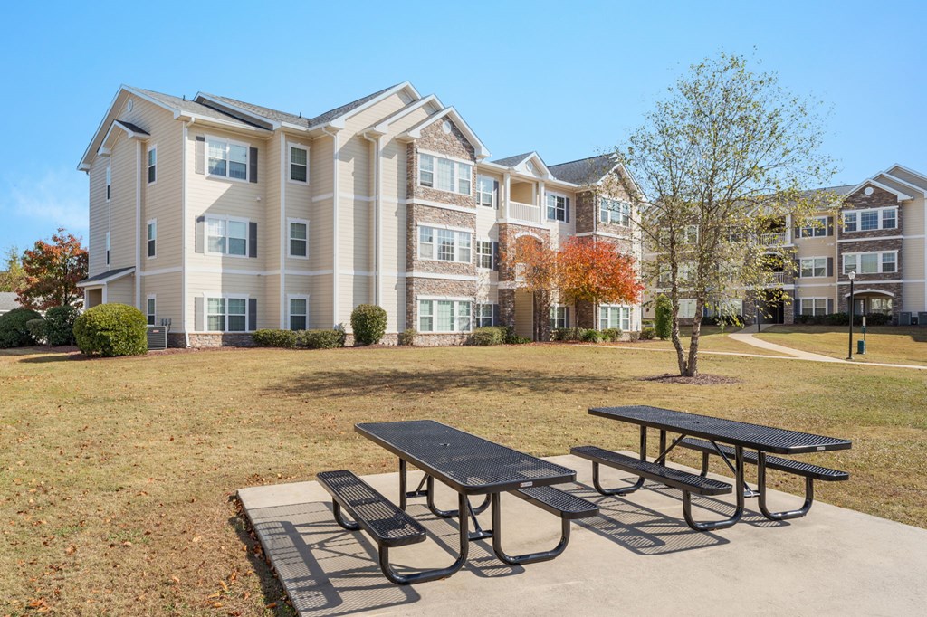 A large apartment complex with a picnic table in front.