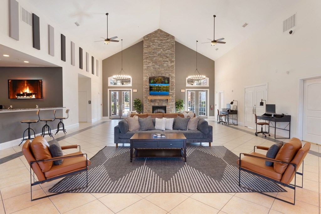 A modern living room with a stone fireplace and a large rug.