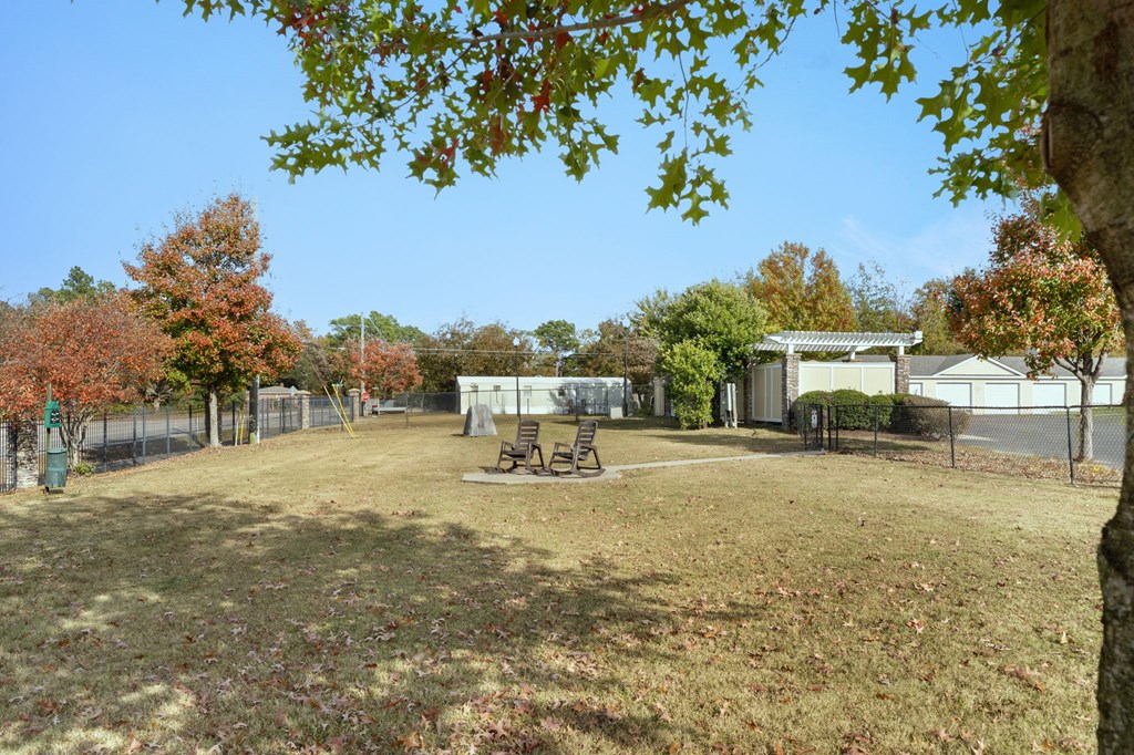 A dog park with a picnic table and a fence.