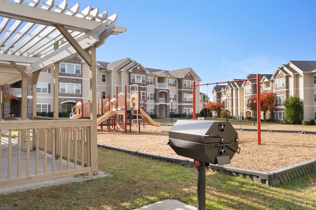 A playground with a slide and a swing set in front of apartment buildings.