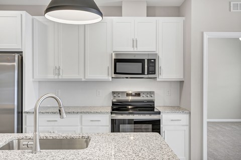 A kitchen with white cabinets and a granite countertop.