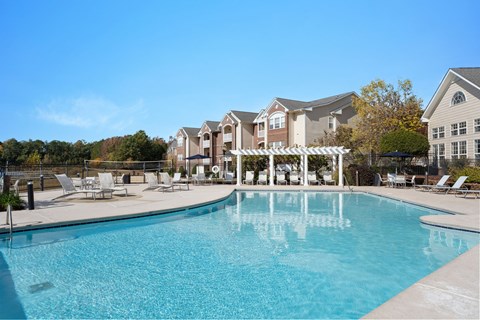 A large swimming pool in front of a building with a white pergola.