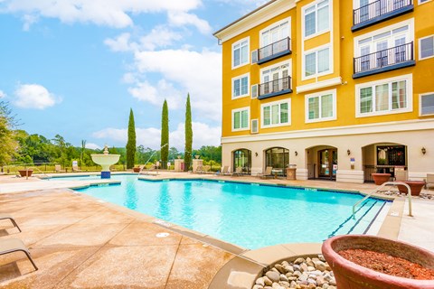 A yellow building with a blue pool in front.