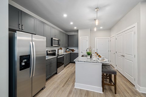 A modern kitchen with a stainless steel refrigerator and a granite countertop.