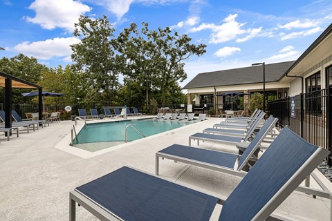A pool with sun loungers and a building in the background.
