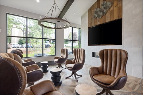 A living room with brown leather chairs and a flat screen TV mounted on the wall.