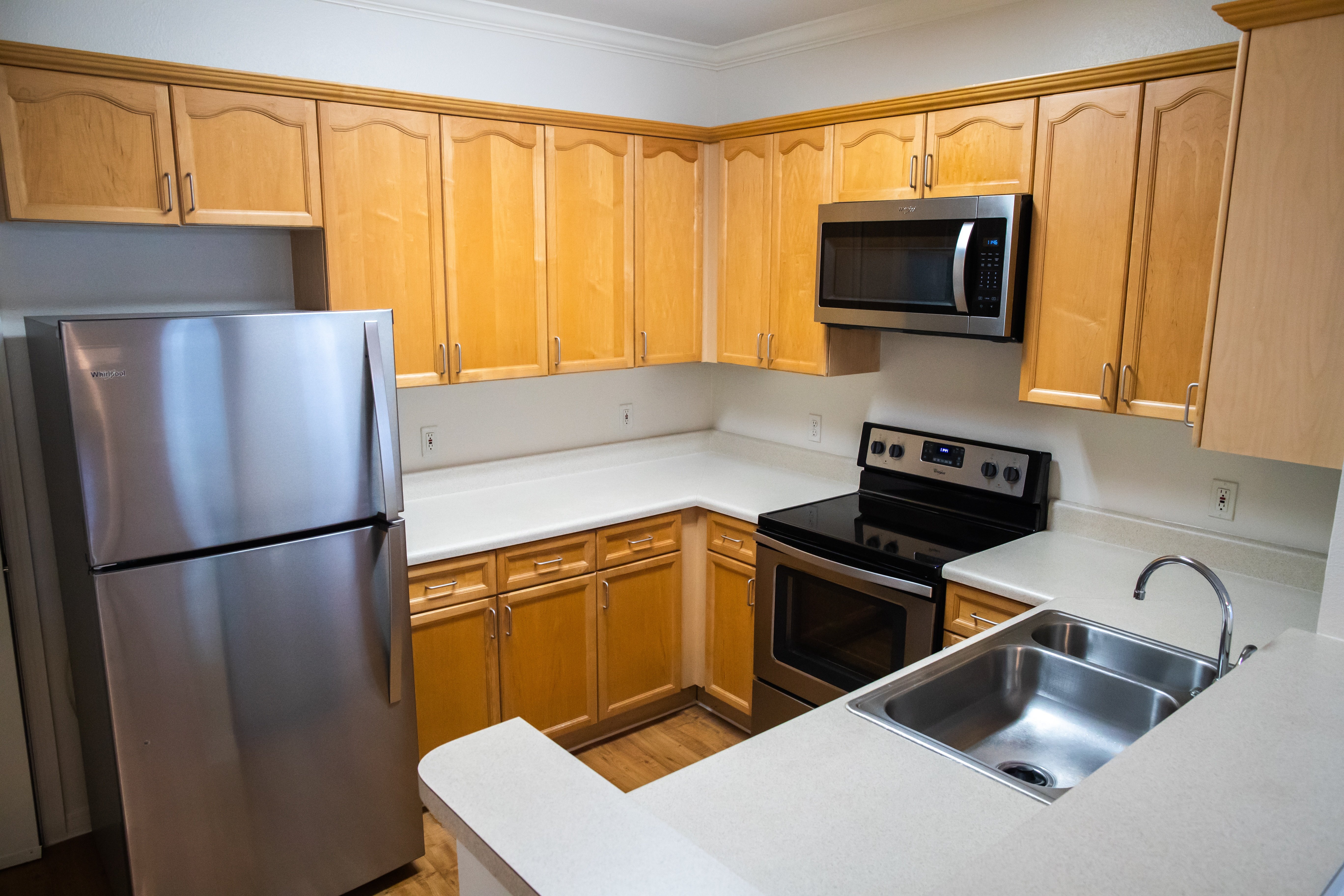 A kitchen with wooden cabinets and a stainless steel refrigerator.