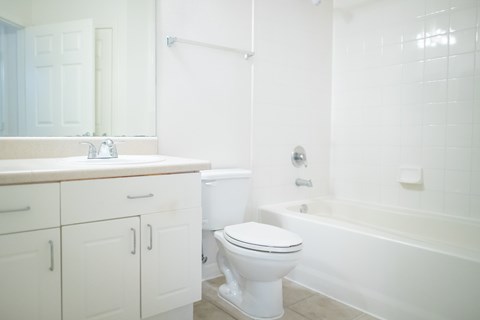 A white bathroom with a toilet, sink, and bathtub.