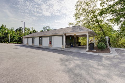 A small white building with a grey roof and a parking lot in front.