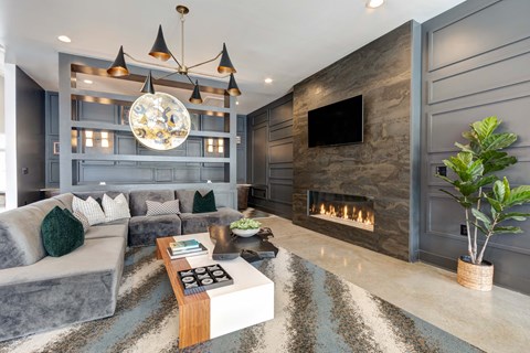 A modern living room with a grey sofa, a fireplace, and a chandelier.