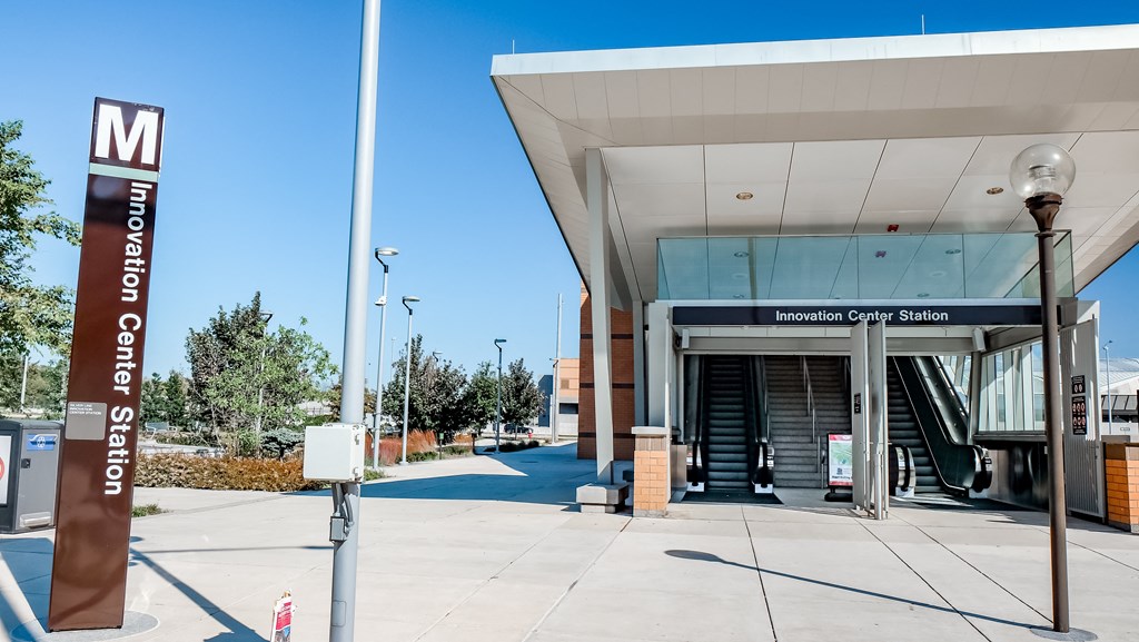 a metro station with a metro sign in front of a building at Makers Rise, Herndon, 20171