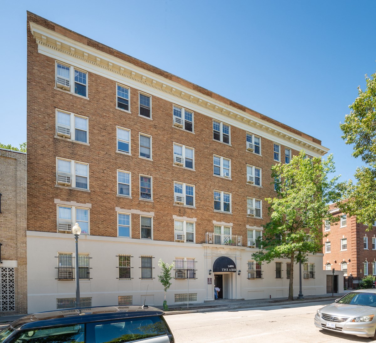 A brown brick building with a black car parked in front.