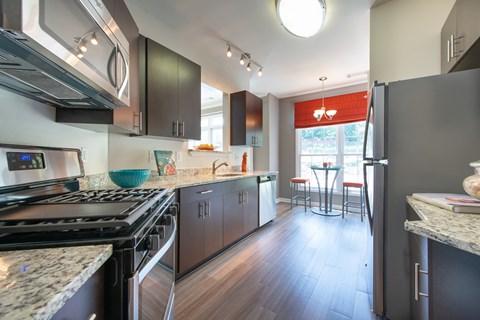 A modern kitchen with dark wood cabinets and granite countertops.