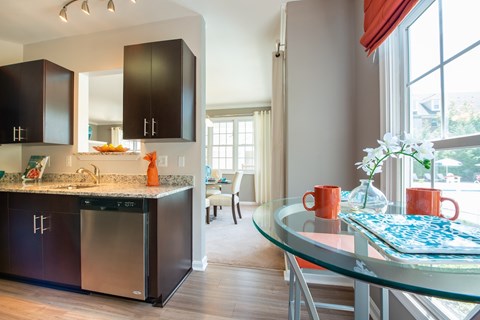 A modern kitchen with a glass table and stainless steel appliances.