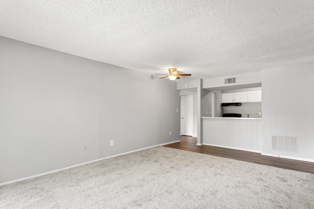 an empty living room with a ceiling fan and a kitchen in the background  at Lakes Edge Apartments, Greensboro, North Carolina