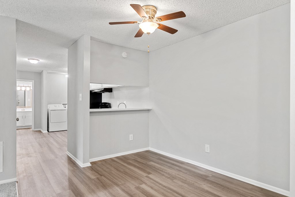 a living room with a ceiling fan and a kitchen in the background  at Lakes Edge Apartments, Greensboro, North Carolina