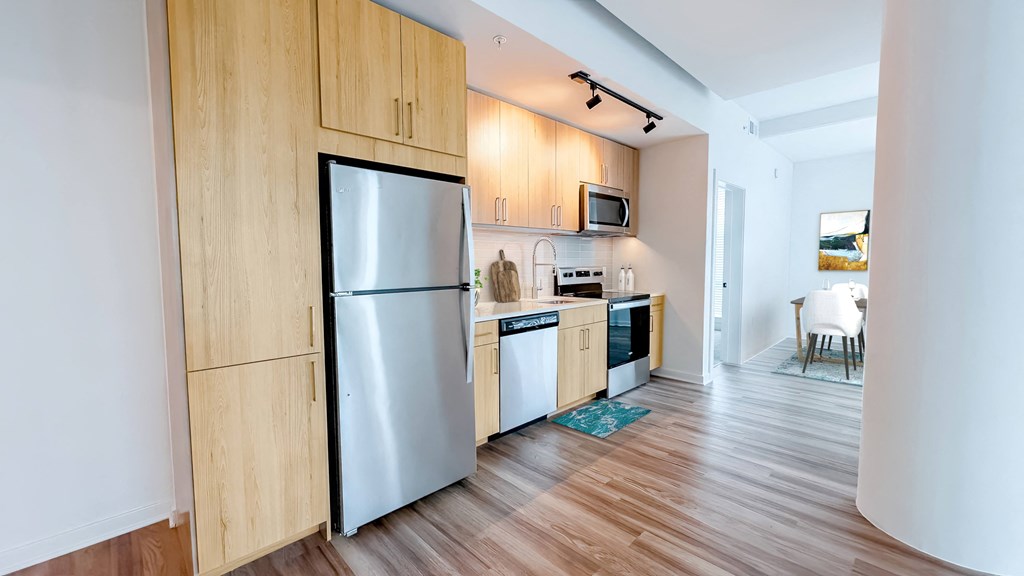 A kitchen with wooden cabinets and a stainless steel refrigerator.at Makers Rise, Herndon, VA
