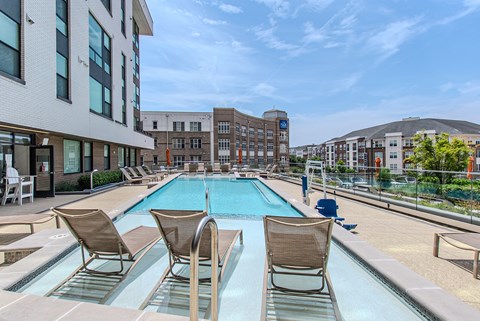 A pool with chairs around it in front of a building.