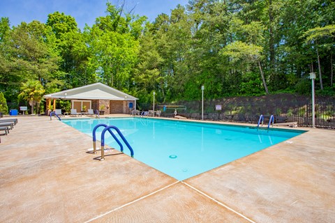 A large swimming pool surrounded by trees and a small building at West Pointe Apartments, North Carolina
