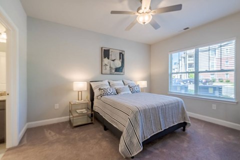 A bedroom with a bed, nightstand, and a ceiling fan.