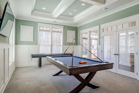 A pool table in a room with a green wall.