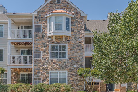 A stone building with a balcony and a tree in front.