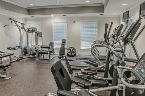 A gym with a variety of equipment including treadmills, weights, and exercise machines.