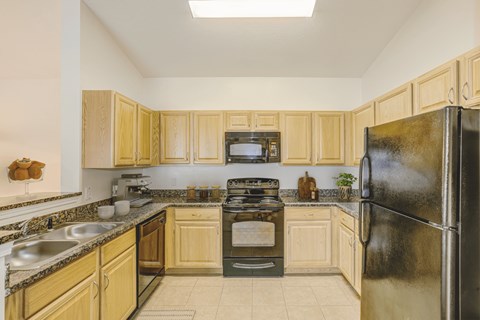 a kitchen with wood cabinets and black appliances at Stone Gate Apartments, Spring Lake, NC