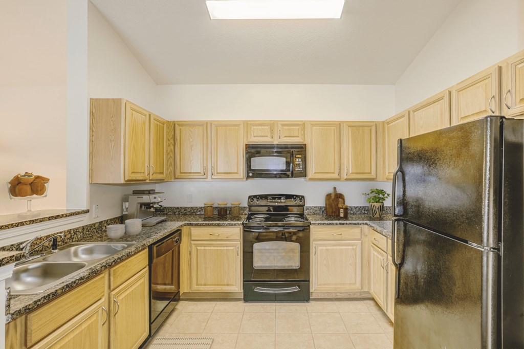 a kitchen with wood cabinets and black appliances at Stone Gate Apartments, Spring Lake, NC